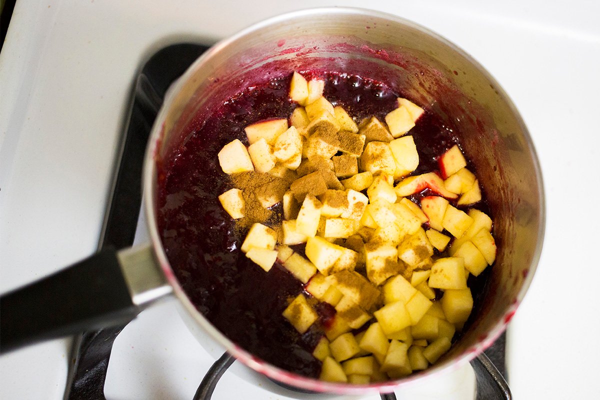 Adding apples and cinnamon to the cranberry sauce.